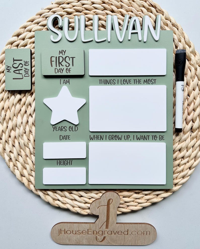 Puede incluir: Un gr&aacute;fico de crecimiento de madera verde con &aacute;reas blancas de borrado en seco para el nombre, la edad, la altura y otros hitos de un ni&ntilde;o. El gr&aacute;fico tiene el texto "My First Day Of" y "My Last Day Of" con una forma de estrella en el medio. El gr&aacute;fico est&aacute; sobre un fondo marr&oacute;n tejido.