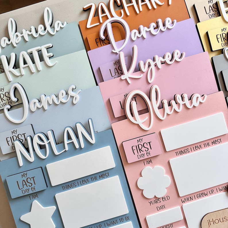 Puede incluir: Un conjunto de letreros de madera personalizados para el primer d&iacute;a de escuela de un ni&ntilde;o. Cada letrero presenta un nombre diferente, como "James", "Nolan", "Kyree" y "Olivia". Los letreros est&aacute;n decorados con letras blancas y tienen un fondo azul claro, rosa o verde claro. Los letreros tambi&eacute;n incluyen secciones para que el ni&ntilde;o pueda completar informaci&oacute;n sobre su primer d&iacute;a de escuela, como su edad, sus cosas favoritas y lo que quiere ser cuando crezca.