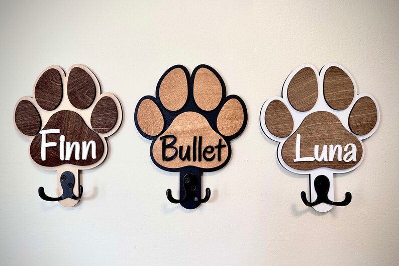May include: Three wooden paw print hooks with double hooks, each with a different dog's name: Finn, Bullet, and Luna.
