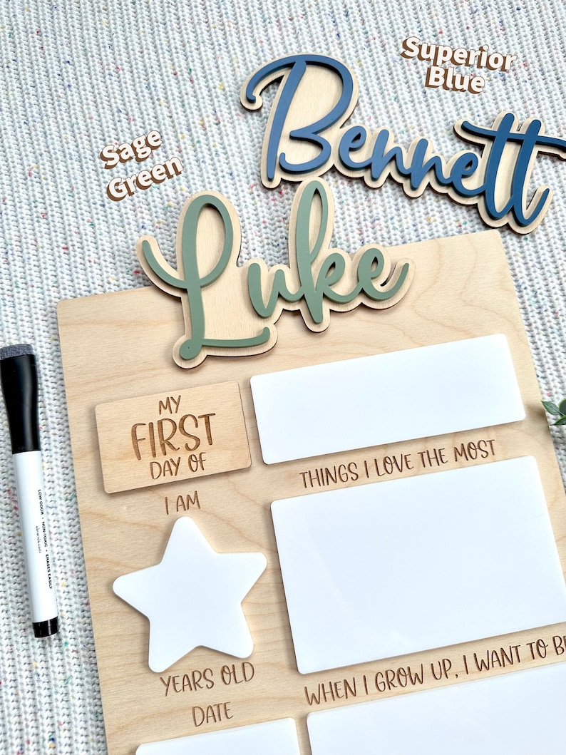 May include: A wooden milestone board featuring laser-engraved text including My First Day Of, I Am, Years Old, Date, Things I Love The Most, and When I Grow Up, I Want To Be. It includes white acrylic inserts for writing and two wooden name cutouts.