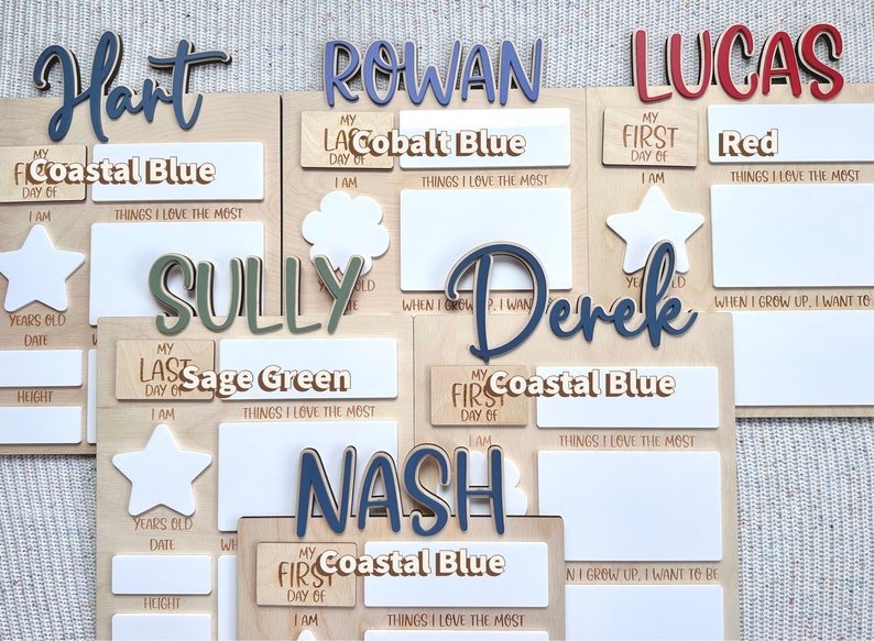 K&ouml;nnte beinhalten: Holzschildchen mit personalisierten Namen wie Hart, Rowan, Lucas, Sully, Derek und Nash. Jedes Schildchen hat Platz f&uuml;r den ersten oder letzten Schultag eines Kindes, sein Alter, Datum, Gr&ouml;&szlig;e und die Dinge, die es am meisten liebt. Die Schildchen sind in verschiedenen Farben bemalt, darunter Blau, Gr&uuml;n und Rot.