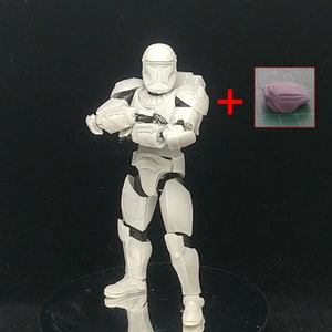 Könnte beinhalten: Weiße Plastik-Actionfigur eines Star Wars Stormtroopers mit einem Blastergewehr. Die Figur steht mit gekreuzten Armen. Die Figur wird mit einem separaten weißen Plastikzubehör verkauft.