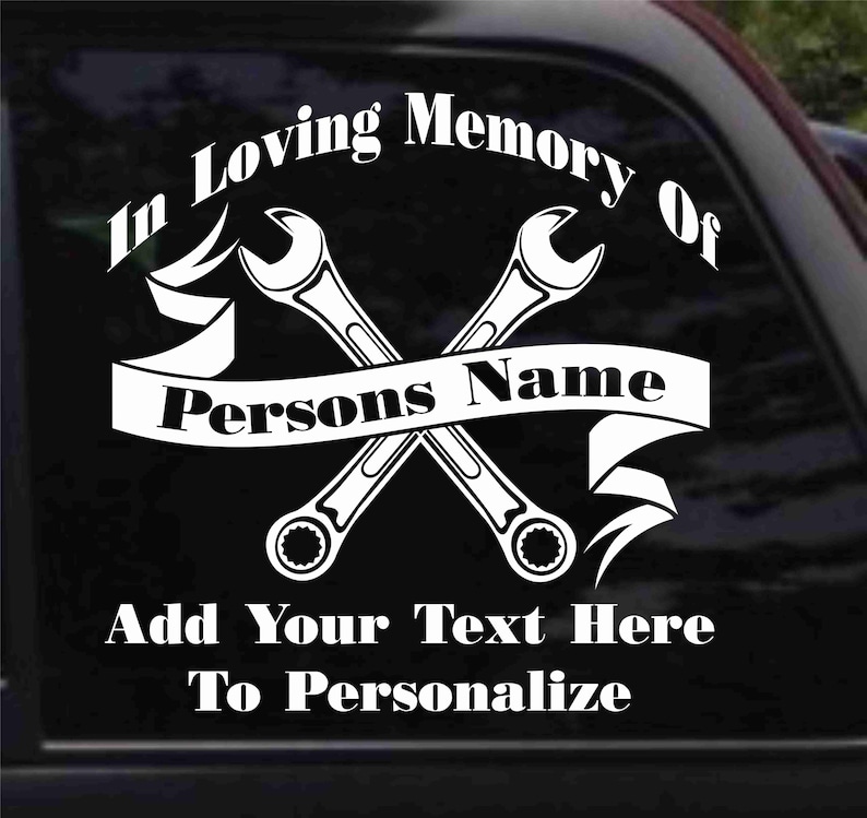 K&ouml;nnte beinhalten: Wei&szlig;er Vinyl-Aufkleber mit zwei gekreuzten Schraubenschl&uuml;sseln und einem Banner mit der Aufschrift "In Loving Memory Of Persons Name". Der Aufkleber enth&auml;lt auch den Text "Add Your Text Here To Personalize".