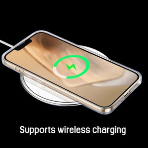 Pu&ograve; includere: Un iPhone dorato con una custodia trasparente &egrave; in carica wireless su un pad di ricarica bianco. Un'icona di fulmine verde &egrave; visibile sullo schermo del telefono.