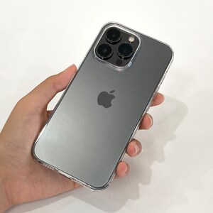 Pu&ograve; includere: Un iPhone nero con una custodia trasparente. Il telefono ha un logo Apple argentato e un gruppo di fotocamere con quattro obiettivi.
