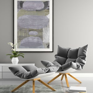 May include: Two gray cushioned chairs with wooden legs, one with a white footrest, in front of a gray wall with a framed abstract painting.