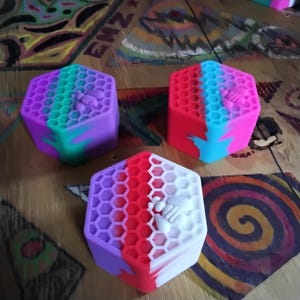 Pu&ograve; includere: Tre stampi in silicone esagonali con un motivo a nido d'ape e un designo di ape. Gli stampi sono in tonalit&agrave; di rosa, viola, blu, rosso e bianco.