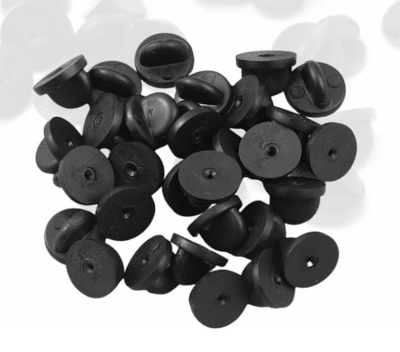 May include: A pile of black plastic pin back closures for badges, buttons, or other crafts.