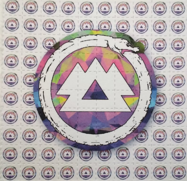 K&ouml;nnte beinhalten: Ein wei&szlig;es Blatt Papier mit einem sich wiederholenden Muster eines lila, blauen und rosa Berglogos. In der Mitte des Blattes befindet sich ein gr&ouml;&szlig;erer Kreis mit einem wei&szlig;en Berglogo, umgeben von einer wei&szlig;en Schlange. Der Hintergrund des Kreises ist ein farbenfrohes abstraktes Design mit lila, blauen, rosa, gelben und gr&uuml;nen Farben.