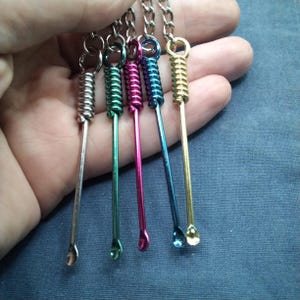 Puede incluir: Colecci&oacute;n de cinco llaveros met&aacute;licos con un extremo en forma de cuchara y un dise&ntilde;o de resorte en espiral. Los llaveros son de color plateado, verde, rosa, azul y dorado. El extremo de la cuchara es peque&ntilde;o y redondeado.