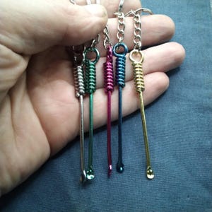 Puede incluir: Una colecci&oacute;n de llaveros coloridos con peque&ntilde;as herramientas de metal. Cada llavero tiene un color diferente, incluyendo plata, verde, rosa, azul y dorado. Las herramientas tienen un dise&ntilde;o de resorte y una peque&ntilde;a cuchara en el extremo.