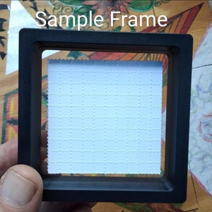 K&ouml;nnte beinhalten: Ein schwarzer Bilderrahmen mit einem wei&szlig;en Passepartout und dem Text "Sample Frame" oben.