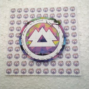 K&ouml;nnte beinhalten: Ein Blatt wei&szlig;es Papier mit einem sich wiederholenden Muster eines lila und wei&szlig;en Berglogos. Eine gr&ouml;&szlig;ere Version des Logos befindet sich in der Mitte des Blattes, mit einem farbenfrohen, abstrakten Design innerhalb des Berglogos. Das gr&ouml;&szlig;ere Logo ist von einem wei&szlig;en Kreis mit einem schwarzen Schlangendesign umgeben.