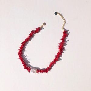 Peut inclure: Un collier en corail rouge avec un pendentif en perle blanche. Le collier est composé de petites pièces de corail irrégulières et a un fermoir en or.