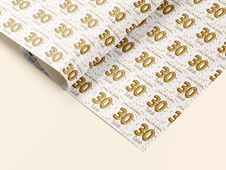 May include: White wrapping paper with a repeating pattern of gold 30th birthday balloons and confetti. The text "Happy 30th Birthday" and the name "Sarah" are repeated throughout the pattern.