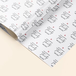 Pu&ograve; includere: Carta da regalo bianca con un motivo ripetuto di cuori rosa e il testo "Happy 30th Birthday Melissa" in corsivo nero.