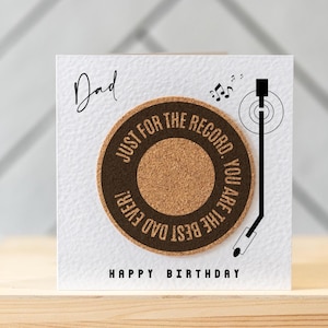 May include: A white card with black text that reads "Dad" and "Happy Birthday". A cork coaster with black text that reads "Just for the record, you are the best dad ever!" is on the card. A black and white illustration of a record player is on the card.