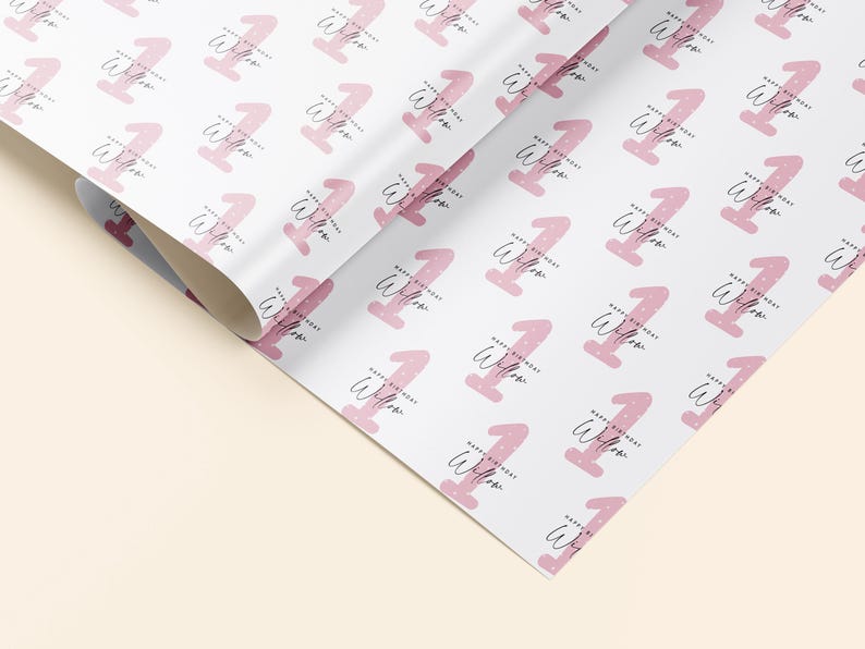 K&ouml;nnte beinhalten: Rosa-wei&szlig;es Geschenkpapier mit einem sich wiederholenden Muster der Zahl eins mit den Worten "Happy Birthday Willow" darauf.