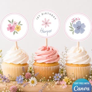 Può includere: Tre cupcakes con decorazioni floreali per un primo compleanno. Le decorazioni sono rotonde con disegni floreali e la scritta "1st Birthday Harper". I cupcakes hanno glassa bianca e rosa e sono decorati con fiori.