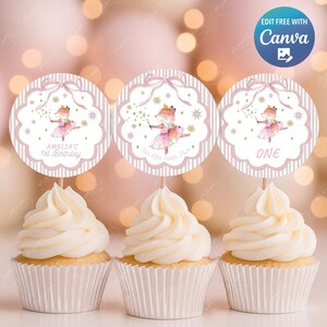 Può includere: Tre cupcakes con glassa bianca, ciascuno sormontato da un decoro rotondo rosa e bianco. I decori presentano un'illustrazione ad acquerello di una volpe in abito da ballerina. Il testo sui decori recita "Amelia's 1st Birthday", "One" e "The Little Sugar Mum".