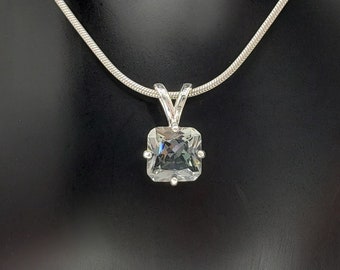 May include: A silver chain necklace with a square-shaped pendant featuring a clear crystal.