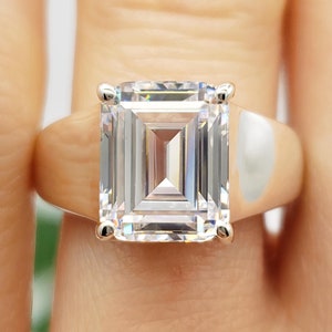 May include: A silver ring with a large, clear emerald-cut gemstone.