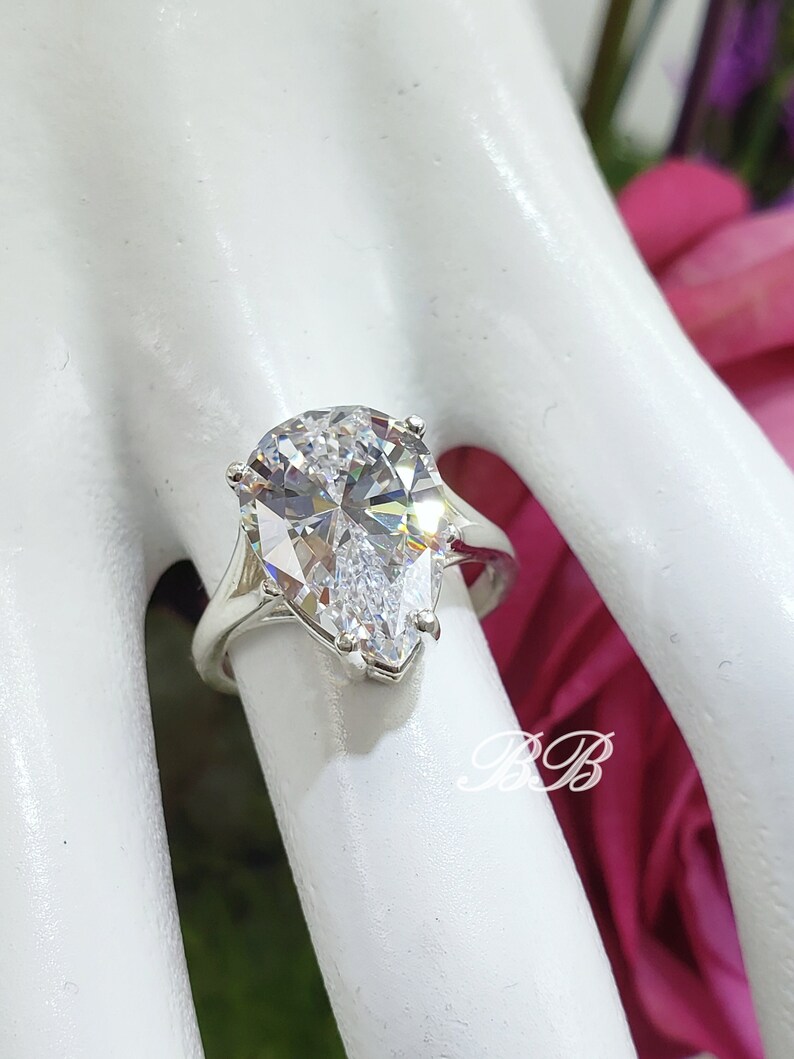 May include: A pear-shaped clear cubic zirconia engagement ring set in a silver band.