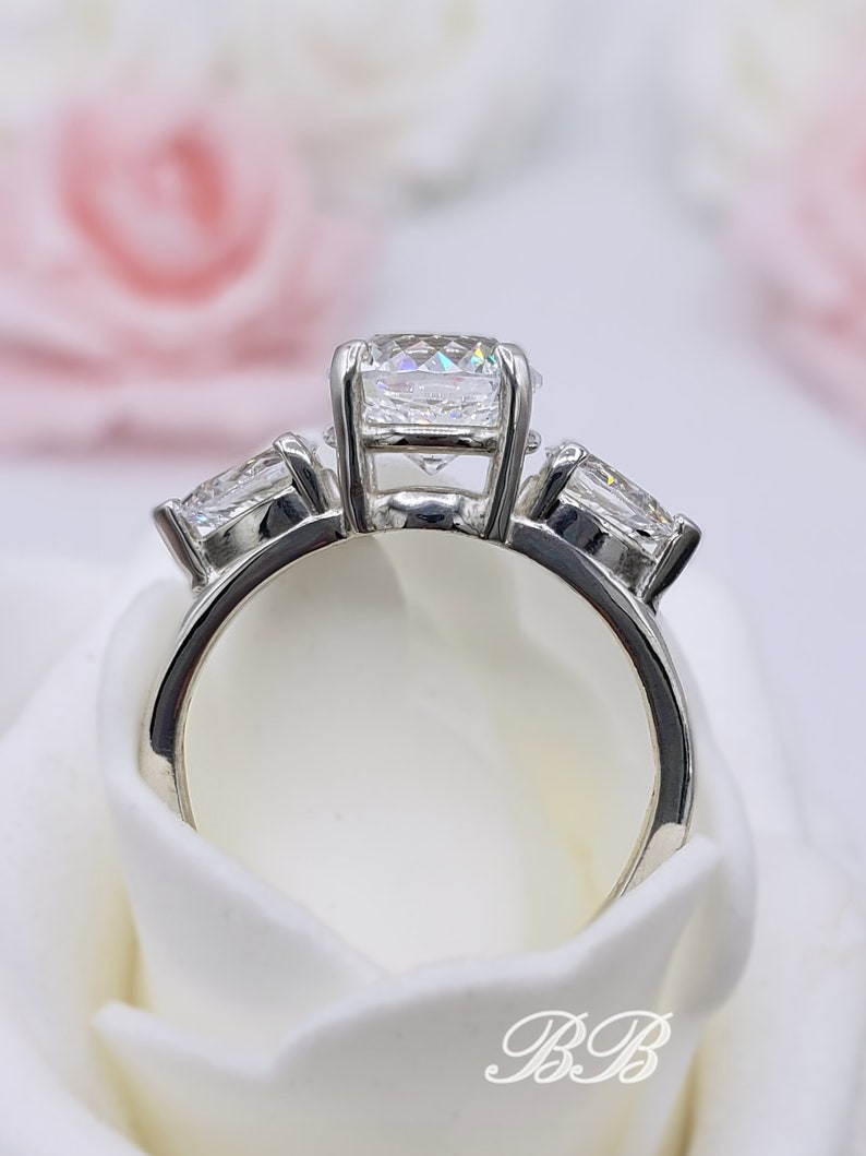 May include: A silver ring with three round diamonds. The center diamond is larger than the two side diamonds.