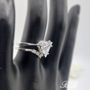 May include: A silver ring with a large triangular-shaped clear stone and smaller clear stones on the band.