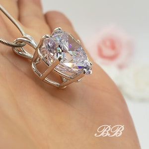 May include: A silver necklace with a large pear-shaped clear crystal pendant set in a cage-like design.