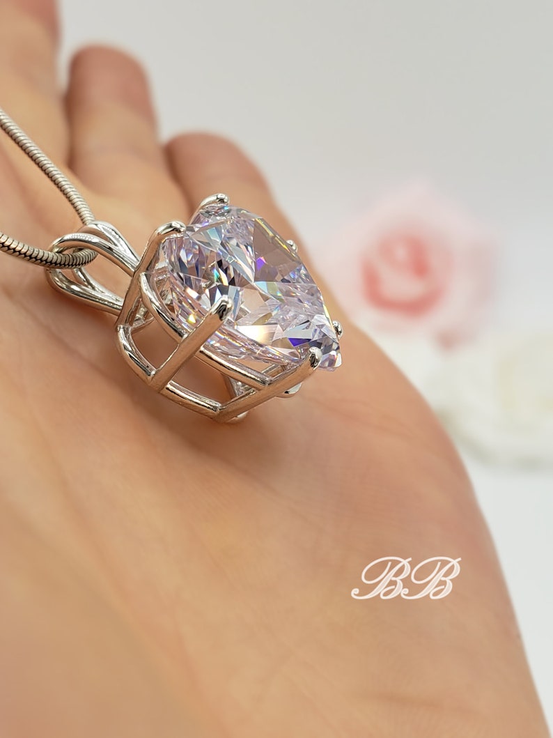 May include: A silver necklace with a large pear-shaped clear crystal pendant set in a cage-like design.