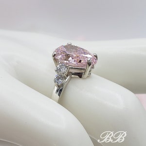 Puede incluir: Un anillo de plata con una gran piedra rosa en forma de pera y piedras redondas transparentes m&aacute;s peque&ntilde;as en la banda.