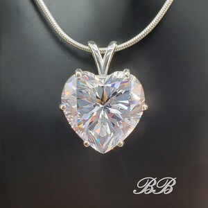 May include: A silver chain necklace with a large, clear heart-shaped pendant. The pendant has many facets and sparkles.
