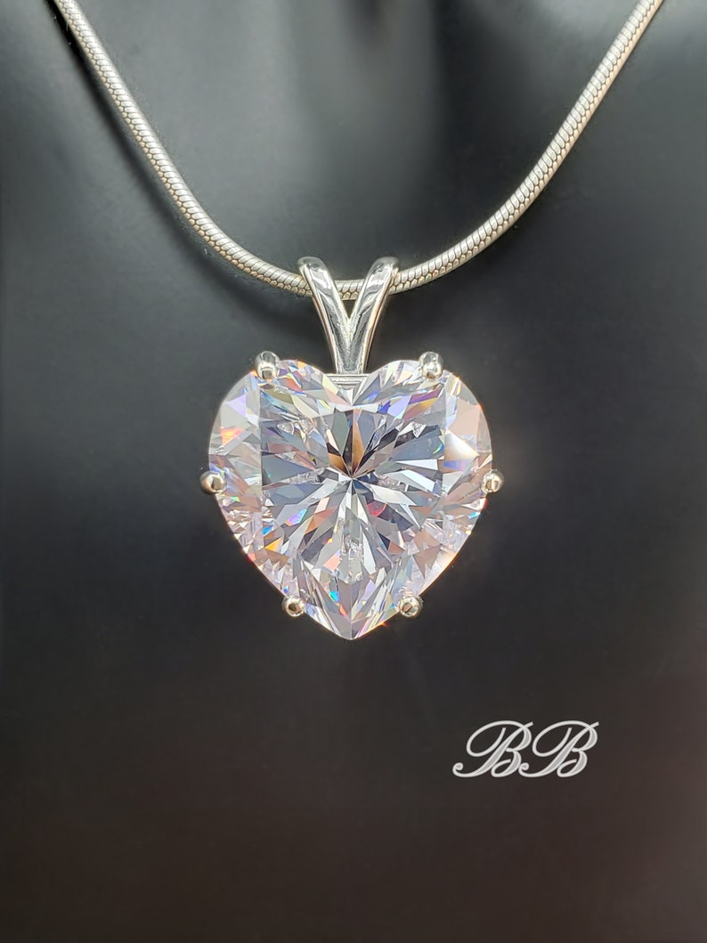 May include: A silver chain necklace with a large, clear heart-shaped pendant. The pendant has many facets and sparkles.