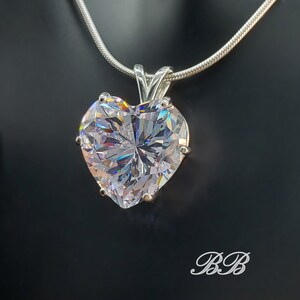 May include: A silver chain necklace with a large, clear heart-shaped pendant. The pendant is faceted and reflects light.