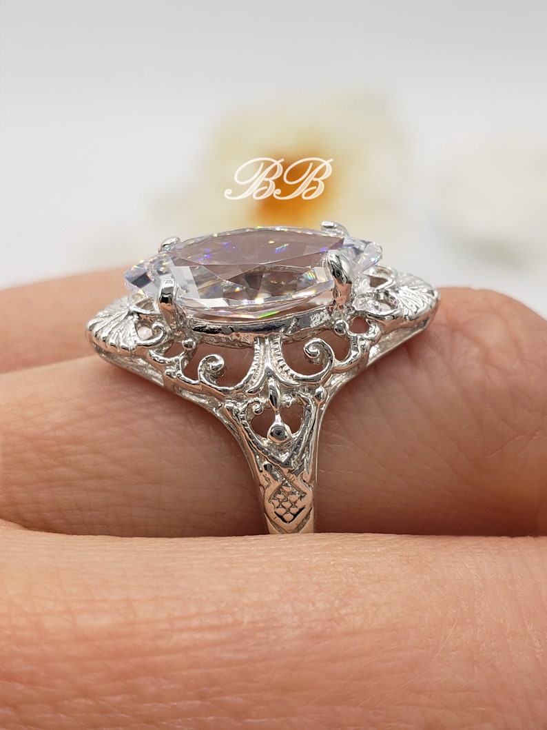 Puede incluir: Un anillo de plata con una gran piedra ovalada transparente engastada en un dise&ntilde;o de filigrana.