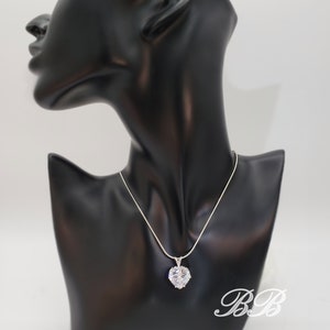May include: A silver chain necklace with a large, clear heart-shaped pendant. The pendant is made of cubic zirconia stones.