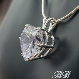 May include: A silver chain necklace with a large, clear, faceted crystal pendant set in a silver cage.
