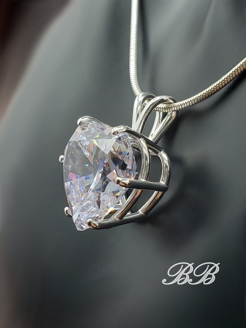 May include: A silver chain necklace with a large, clear, faceted crystal pendant set in a silver cage.