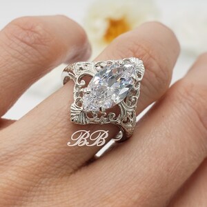 Puede incluir: Un anillo de plata con una gran piedra transparente de forma marquesa engastada en un dise&ntilde;o de filigrana.