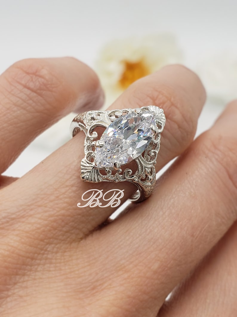 Puede incluir: Un anillo de plata con una gran piedra transparente de forma marquesa engastada en un dise&ntilde;o de filigrana.