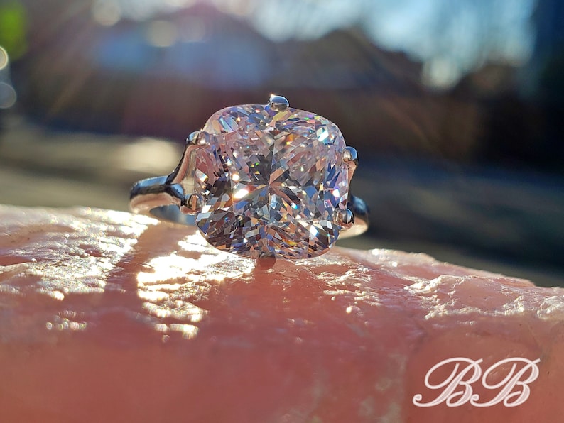May include: A silver ring with a large, clear, cushion-cut gemstone.