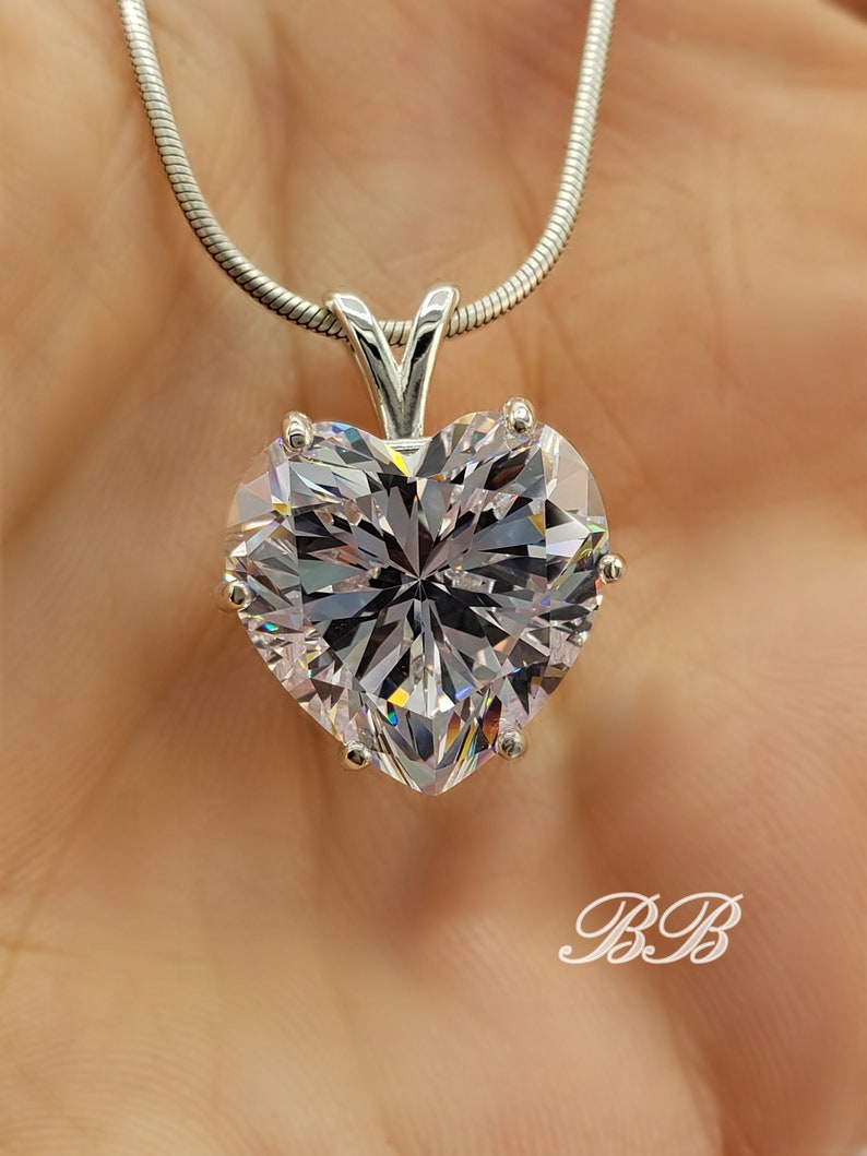 May include: A silver chain necklace with a large, clear heart-shaped pendant. The pendant has many facets and sparkles.