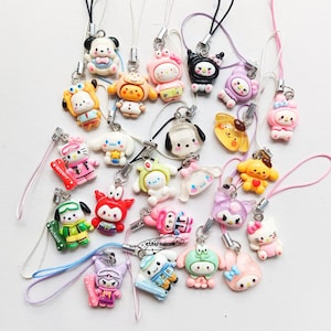 May include: A collection of colorful character phone charms, featuring various designs like cats, dogs, and other cartoon figures. Each charm has a lanyard for easy attachment. The charms are in various colors, including pink, yellow, and blue.