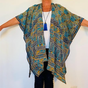May include: A patterned kimono in shades of teal, gold, and navy blue. The open-front garment features an intricate design with paisley and geometric elements. The kimono is worn over a white top and black pants.