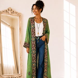 May include: A long, sheer green duster cardigan featuring dark maroon velvet trim along the front opening and cuffs. The trim is decorated with intricate floral embroidery, small circular mirrors, and metallic beadwork throughout the garment.