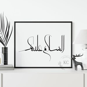 May include: Black and white calligraphy print with the Arabic phrase "Al Salam Alaykum" in a modern style. The print is framed in a black frame and is hanging on a white wall.