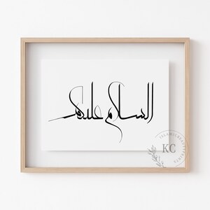 May include: A framed print with the Arabic phrase "Assalamu Alaikum" in black calligraphy on a white background.