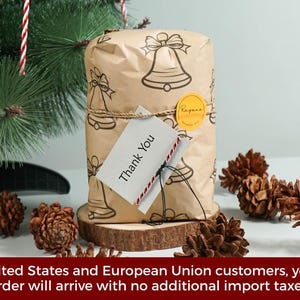 May include: A rectangular package wrapped in brown paper featuring a black line-art bell pattern. The package is tied with twine, secured with a round yellow sticker, and includes a white tag with the printed text Thank You in black ink.
