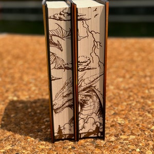 May include: Two hardback books with brown dragon illustrations on the spines. The books are set against a light brown background.